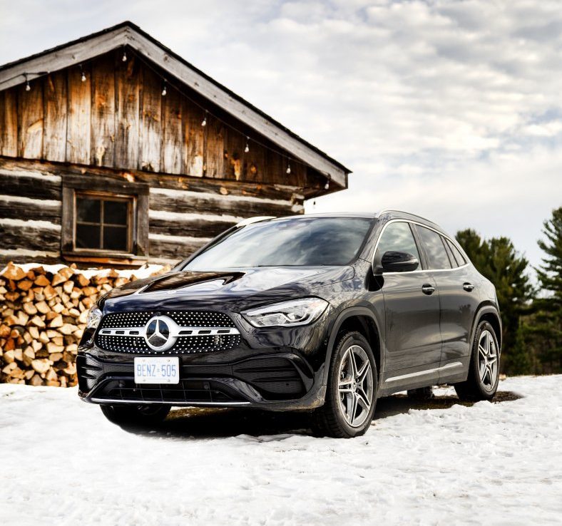 Mercedes Benz GLA parked on snow against wood cabin