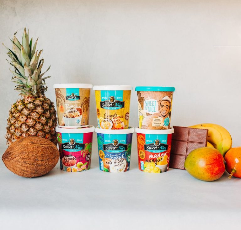 Six Neale's Sweet N' nice ice cream cartons surrounded by a pineapple, a coconut, chocolate, and mangos