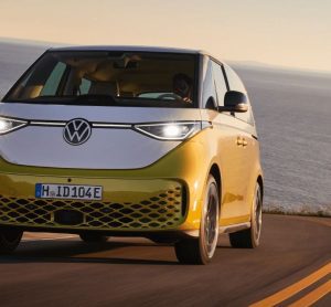 Yellow Volkswagen ID. Buzz electric vehicle driving down a road by the ocean