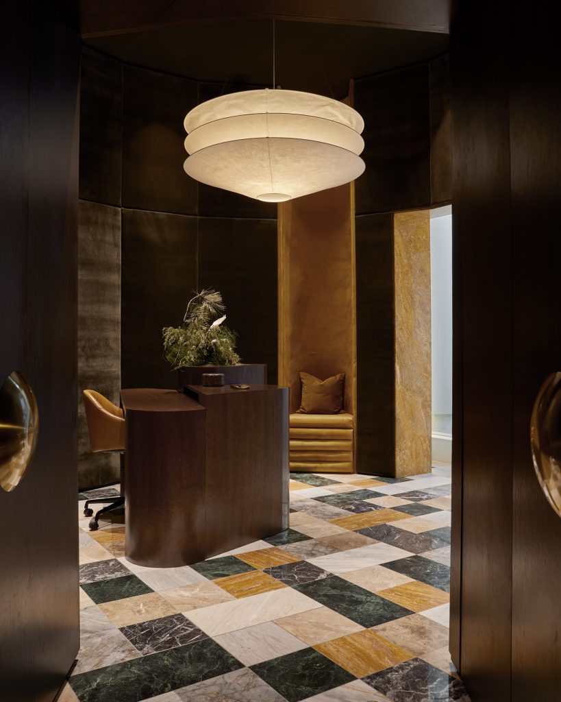 Entrance to a luxury dental clinic with different coloured mosaic tiles and dark wood features.