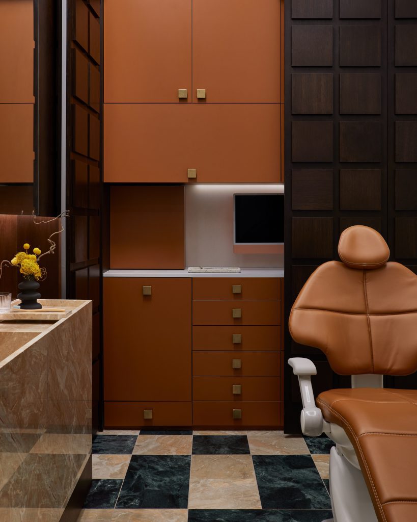 Beautiful dental room with tan leather char, mosaic marble floors, marble countertops and dark wood features.